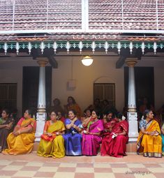 a group of women in colorful saris sitting on the front steps of a building