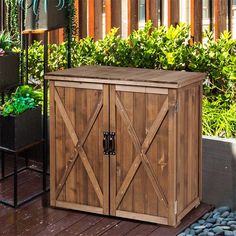 a wooden storage box sitting on top of a deck next to plants and flowers in pots