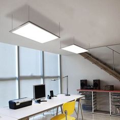 an office with two computers and yellow chairs