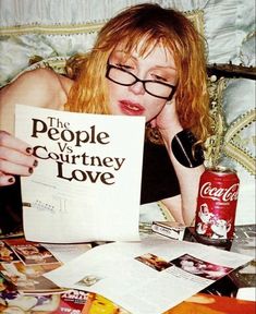 a woman laying on top of a bed with a book in front of her face