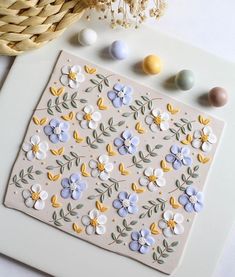 an easter card with flowers and eggs on it next to a basket full of painted eggs