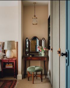 a room with a chair, table and mirror on the wall next to a door