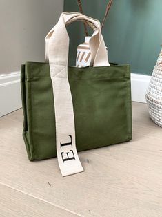 a green bag sitting on the floor next to a vase