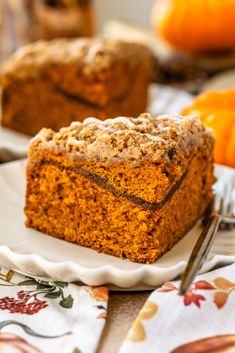 a piece of cake sitting on top of a white plate next to an orange pumpkin