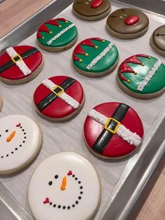 decorated cookies in the shape of santas and snowmen on a baking sheet, ready to be baked