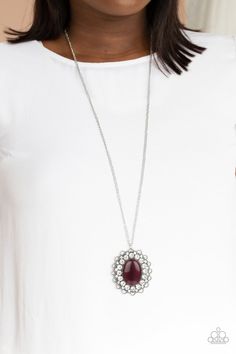 a woman wearing a necklace with a large red stone in the center and white beads around it