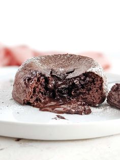 a chocolate cake on a white plate with one piece cut out and the other half eaten