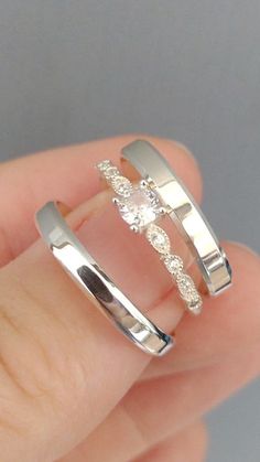 someone is holding two wedding rings in their hand, one with a diamond on it