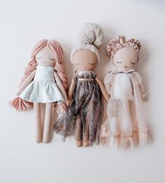 three dolls sitting next to each other on top of a white surface with one doll in the middle