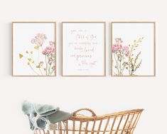 three pink flowers are hanging on the wall next to a wicker basket with a blanket