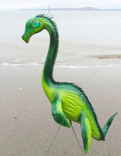 a green and black dragon statue on the beach