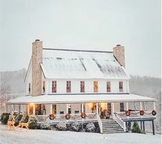 a large white house with christmas lights on the front porch and stairs leading up to it