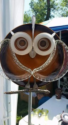 an owl shaped glass dish on top of a metal stand in front of a tent