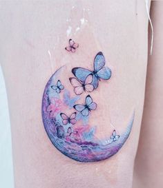 a woman's thigh with butterflies on it and the moon in the sky behind her