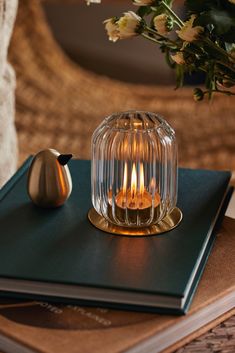 a candle is sitting on top of a book next to a vase with flowers in it