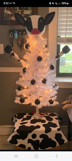 a white christmas tree decorated with black and white ornaments, lights and cow head decorations