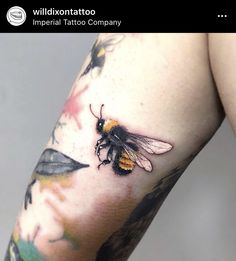 a close up of a person's arm with a tattoo on it and a bee