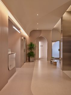 an empty hallway with urinals and plants in the corner on either side of the wall