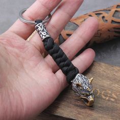 a hand holding a black rope with an animal head on it and a keychain