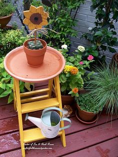 a potted sunflower sitting on top of a wooden table next to a watering can