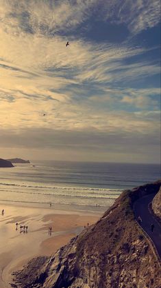 people are walking on the beach and flying kites in the sky over the water