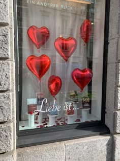 a window display with red heart shaped balloons