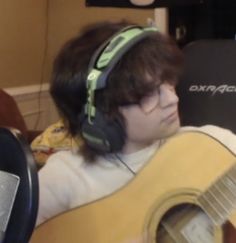 a young man wearing headphones and holding a guitar