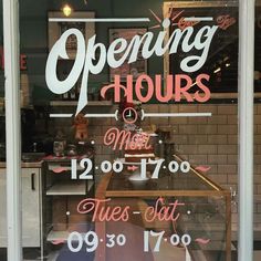 a store front window with the words opening hours written on it