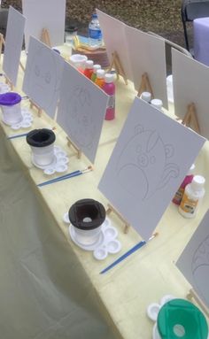 the table is set up with art supplies for kids to draw and paint on canvases