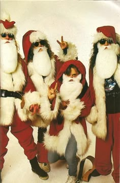 three men dressed as santa clause standing next to each other with their hands in the air