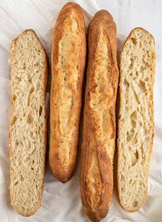 three loaves of bread sitting next to each other on a white tablecloth covered surface