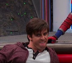 a man in a red and white shirt sitting next to another person wearing a spiderman costume