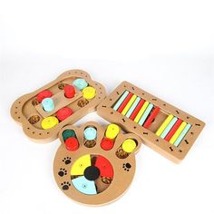 three wooden toys sitting on top of a white table with lots of different colored shapes and sizes