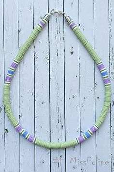 a green and purple beaded necklace on a white wooden background with the words miss pune written below it