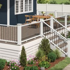 a deck with white railings and wooden table in front of a blue house on a sunny day