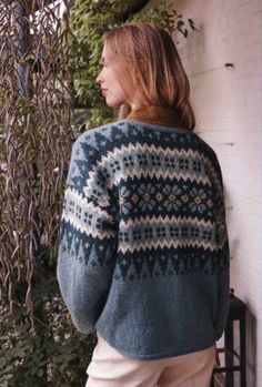 a woman standing next to a wall wearing a sweater