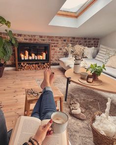 a person sitting in a living room reading a book and holding a cup of coffee