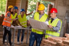 men in safety vests and hard hats looking at plans