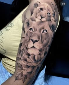 a woman's arm with a lion and flower tattoo on her left shoulder,