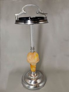 a silver table lamp with an orange glass bulb on it's base and a metal stand