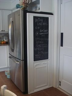 a refrigerator with a chalk board attached to it in a kitchen next to white cabinets