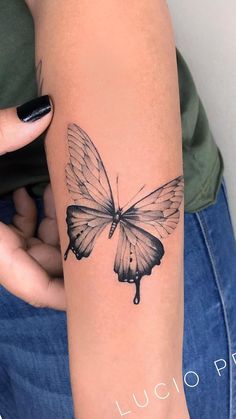 a woman's arm with a black and white butterfly tattoo on the left forearm