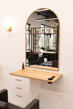 a mirror sitting on top of a wooden table next to a chair and desk with two black chairs