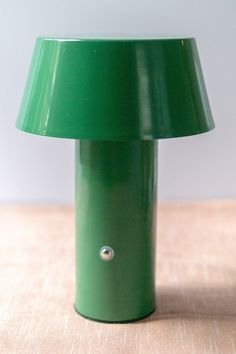 a green lamp sitting on top of a wooden table