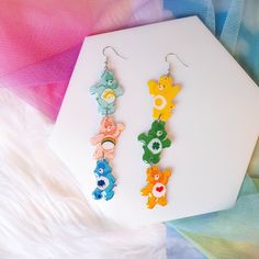 These super cute stacked Care Bears dangle earrings feature Cheer Bear, Tenderheart Bear, Wish Bear, Good Luck Bear, Grumpy Bear, and Funshine Bear.  These earrings are made of machine-cut, lightweight, PVC polymer, and they're sealed with clear, glossy resin. They're finished with hypoallergenic, nickel-free hooks. Hardware swaps are available upon request. Each bear measures roughly 1in tall. The total length of these earrings is about 4in, including the hooks.  Due to the handmade nature of my earrings, please allow for slight variations in color or size. Care Bears Earrings, Care Bear Earrings, Diy Earrings Studs, Tenderheart Bear, Good Luck Bear, Grumpy Bear, Funshine Bear, Cheer Bear, Jewelry Making Business