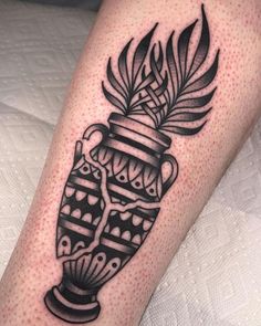 a black and white tattoo on the leg of a person with a vase in it