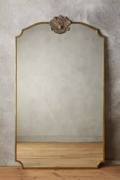 a large mirror sitting on top of a wooden floor next to a wall mounted shelf