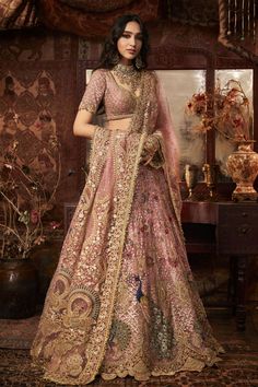 a woman in a pink and gold lehenga