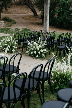 rows of black chairs with white flowers in the back and on the ground near each other