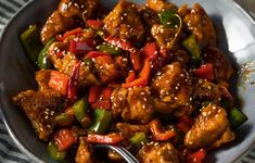 a bowl full of chicken and peppers with sesame seeds on the side, ready to be eaten